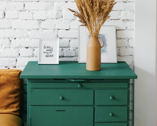 image of green dresser with a vase and framed artwork